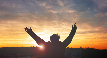 Praise and worship concept: Silhouette human raising hands to praying God on blurred cross with...