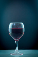 bright beautiful red wine pouring jet into a transparent glass cup isolated on a wite background