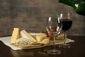 Red wine poured into a glass  with cheese board 