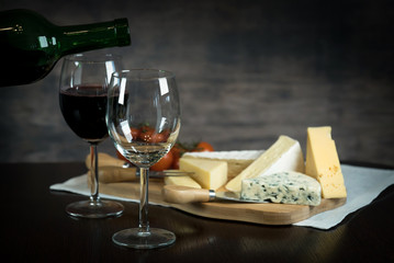 Red wine poured into a glass  with cheese board 