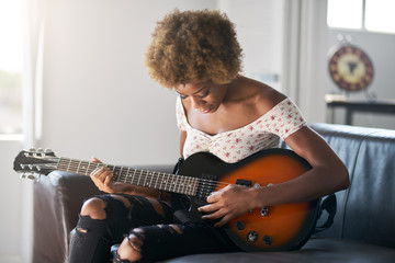 female african american musician playing practicing to play electric guitar at home