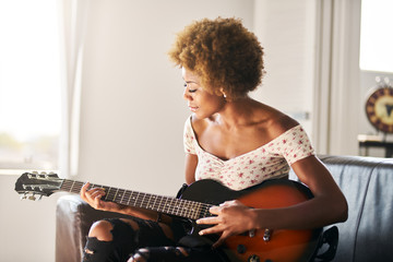 african american woman playing guitar at home - Powered by Adobe