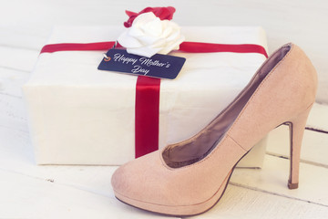 white gift with beautiful red and white flower and tag with happy women's day and pink pumps