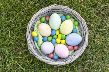 Close-up of a wooden basket full of colorful easter eggs on a grass field. Traditional hand-painted eggs for easter celebration. Concept for easter, spring and tradition