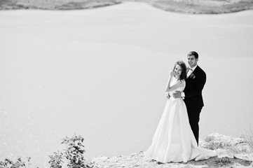 Wedding couple at breathtaking landscape with rock and lake.