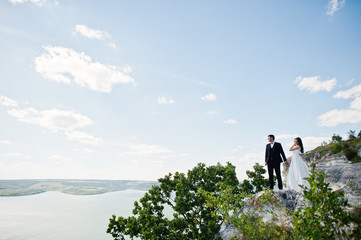 Obraz premium Wedding couple at breathtaking landscape with rock and lake.
