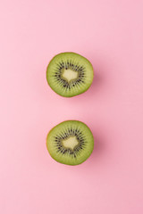 The concept of healthy eating. Half-cut kiwi on a pastel pink background. Top View.