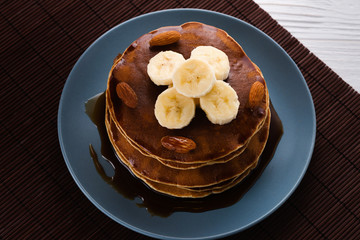 Pancakes with caramel, banana and nuts decorated with cranberries and mint with juice.