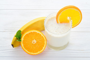 Smoothies with bananas and oranges, a sprig of mint on a white background. Space for text or design.