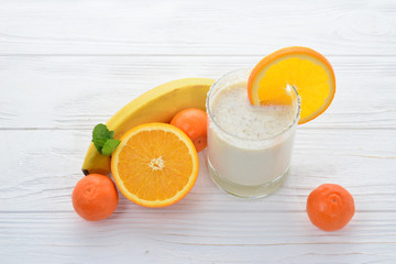 Smoothies with bananas and oranges, a sprig of mint on a white background. Space for text or design.