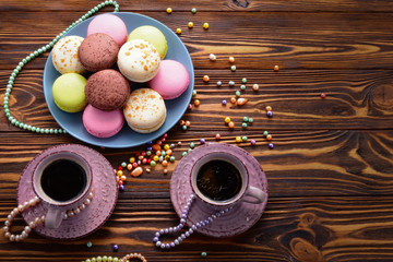 Cake macaron or macaroon with coffee on a wooden background. Space for text or design.