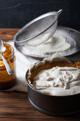 Fototapeta premium Banoffee pie with a jar of caramel and flour on the wooden background 