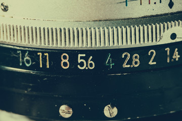 Old manual control lens body. Scratches and dirt. Close-up on the numbers of aperture ring. Retro style