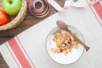 Yogurt with granola in a bowl, Apple and tomato on wooden table, Healthy and Diet concept