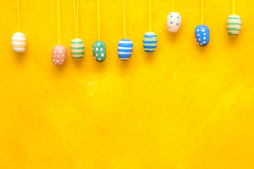 Painted Easter eggs hanging on yellow background.