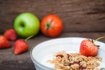 Greek yogurt with granola and strawberry in a bowl with green apple and tomato, Healthy food