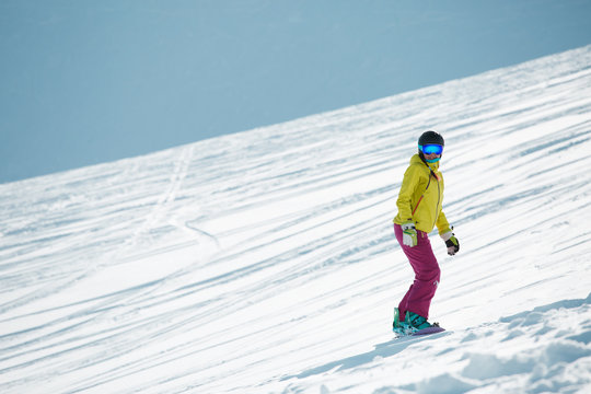 Image of sports woman in helmet and mask, snowboarding from mountain slope