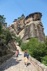 Two female tourists take a walk on the Meteora monasteries, Greece.