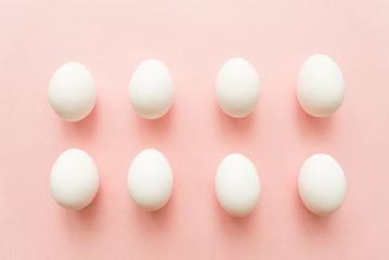 A lot of white eggs on pink pastel background. minimal concept. top view