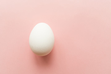 One white egg on pink pastel background. minimal concept. top view