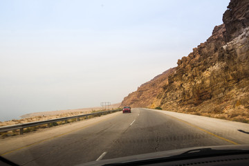Desert highway and mountains through car window not far from Dead sea