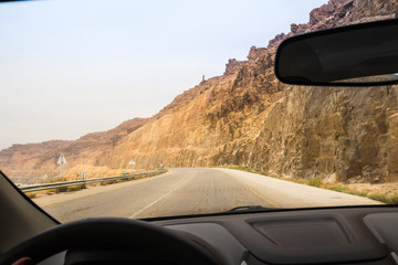 Fototapeta na wymiar Desert highway and mountains through car window not far from Dead sea