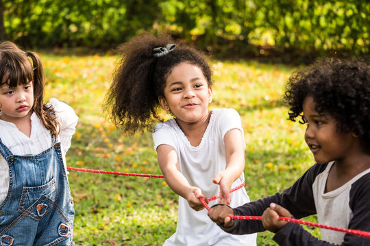 A Little Girl Playing Tug Of War With Her Friends In A Park