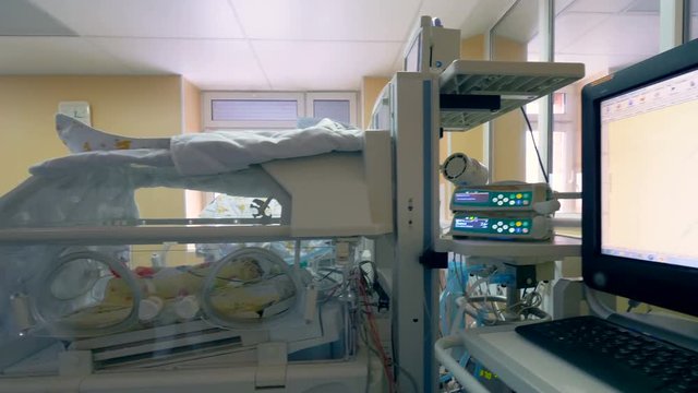 Medical box with a new born baby and close up of a hospital monitor