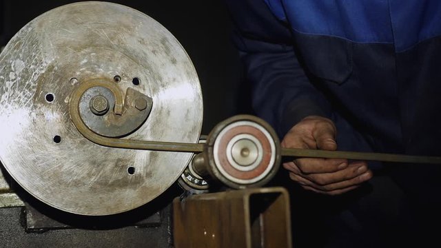 Male worker bends the metal rod on the machine. Manufacturing of a designer part from a metal rod