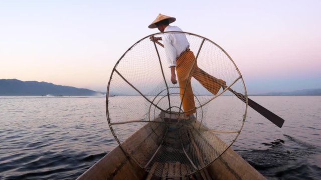 Inle Lake intha fisherman rowing boat in traditional style at sunset, Shan State, Myanmar (Burma).