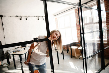 Portrait of the cheerful cheerful girl of the blonde in an interior in style the loft. The woman in...