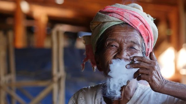 Old lady of Pa'O ethnic minority smoking a Burmese cigar at Indein village near Inle Lake, Shan State, Myanmar (Burma).