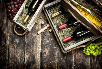 Wine background. Bottles of red and white wine in old boxes.