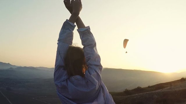 Young woman rise up hands to the wind in front of mountains
