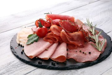 Food tray with delicious salami, pieces of sliced ham, sausage, tomatoes, salad and vegetable - Meat platter with selection