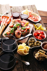 Italian antipasti wine snacks set. Cheese variety, Mediterranean olives, pickles, Prosciutto di Parma, tomatoes, artichokes and wine in glasses