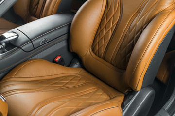 Modern Luxury car inside. Interior of prestige modern car. Comfortable leather red seats. Brown perforated leather cockpit with isolated Black background. Modern car interior details
