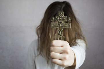 girl holding a cross. the concept of religion.