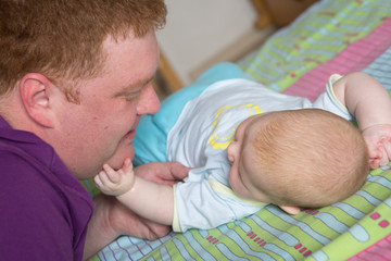 The young father looks at the little breast daughter with a smile