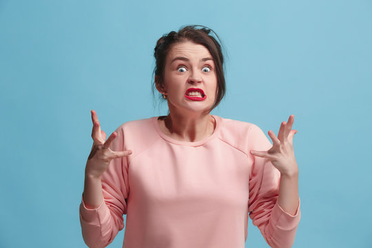 Portrait of an angry woman looking at camera isolated on a blue background