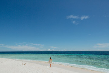Fototapeta na wymiar back view of girl walking on sandy beach at Thoddoo island, Maldives