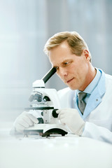 Clinical Test. Scientist With Microscope In Laboratory.
