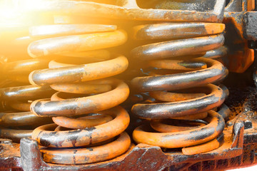 Huge steel spring shock absorbers black and rusty close up.