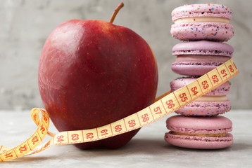 Close-up view of apple, macarons and measuring tape. Concept of nutrition