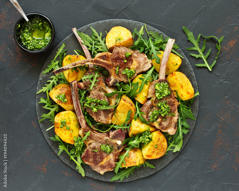 Wall mural Chops of lamb on bone, with baked potatoes and pesto sauce.