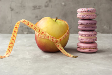 Close-up view of apple, macarons and measuring tape. Concept of nutrition