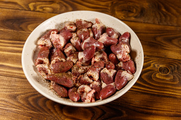 Raw chicken hearts on wooden table