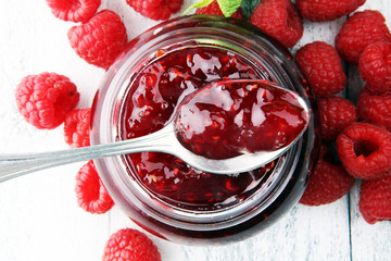 raspberry jam with fresh raspberries and mint. marmalade on spoon and jar.