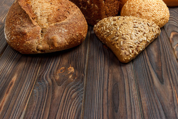 Assortment of baked bread on dark wooden background. Bakery and grocery food store concept. Flat lay with space for text