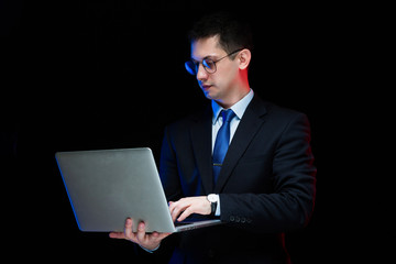 Portrait of confident handsome stylish businessman holding laptop in his hands on black background